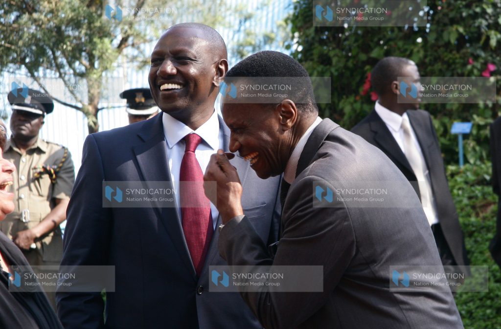 Deputy President William Ruto shares a joke with Education Cabinet Secretary Jacob Kaimenyi