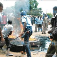 Police officer and protesters jointly put off fire from burning tires