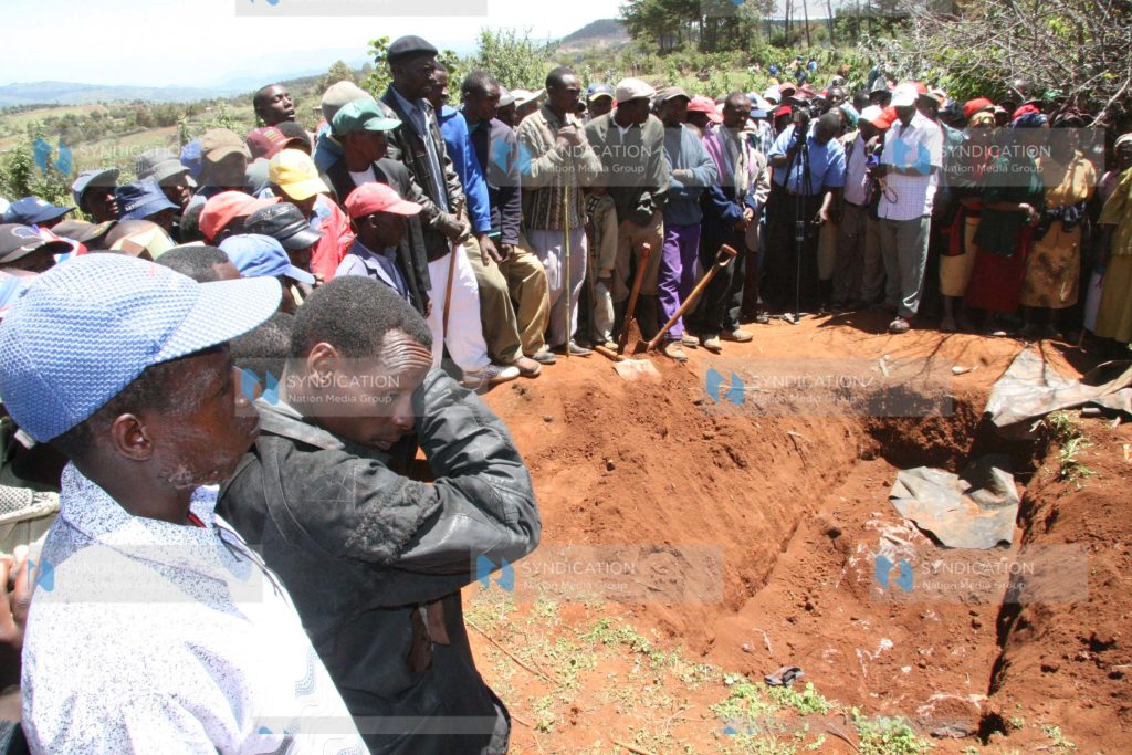 Members of the public mill at a scene where seven bodies of people from one family who were killed during post-election violence