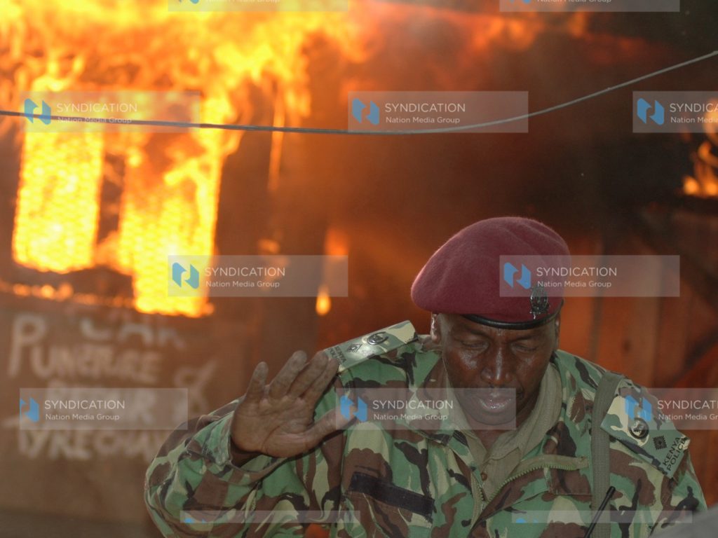 A General service unit police officer runs for his life from a fire break during the post-election violence