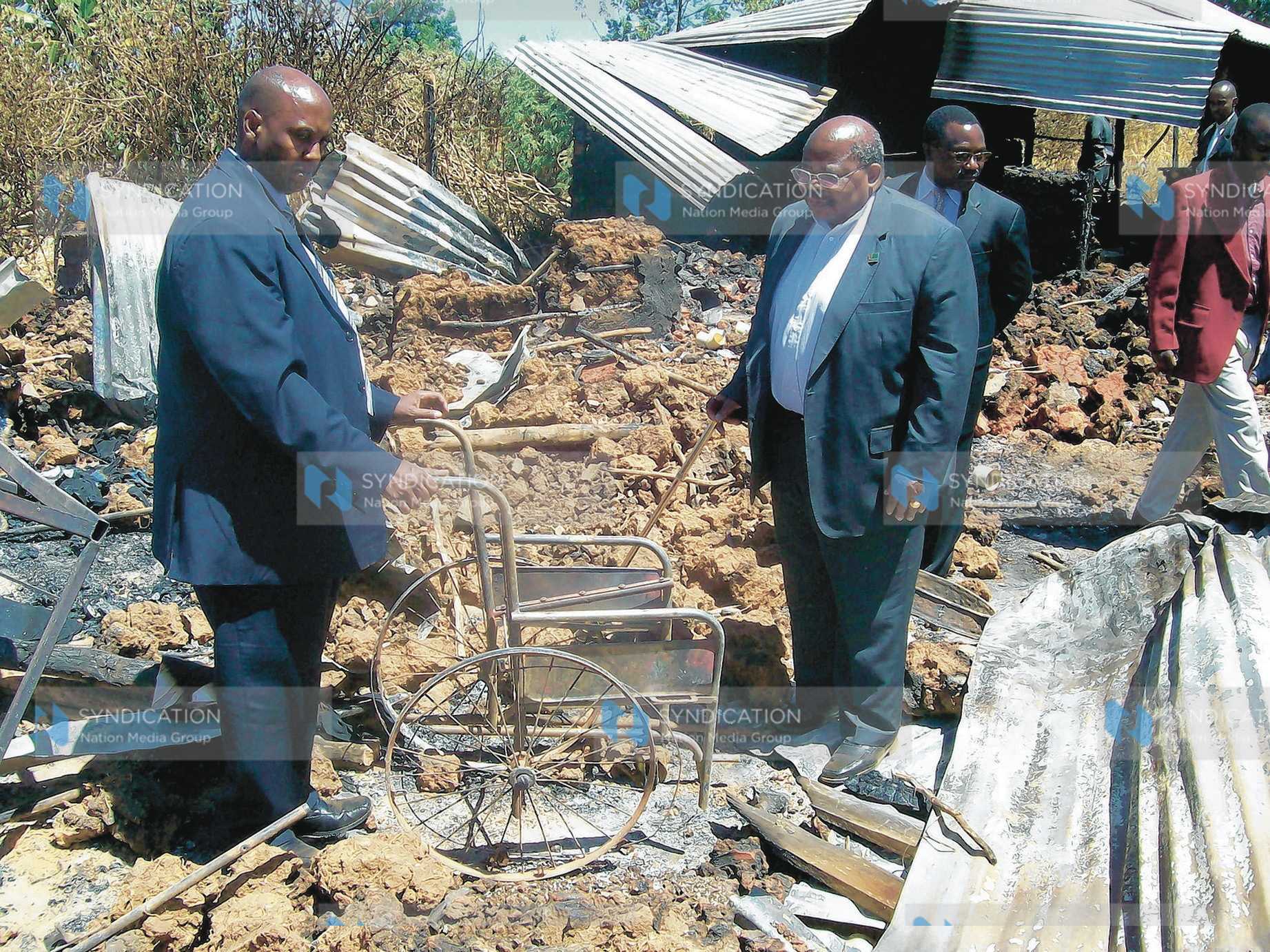 Former Tanzania president Benjamin Mukapa looks at a wheelchair of one of the victims of Kenya Assemblies of God Church in Kiambaa