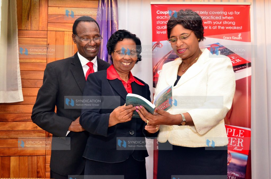 (from right) Youth and Gender Affairs Prof Margaret Kobia, Grace and her Husband James Kimathi sample the book titled 
