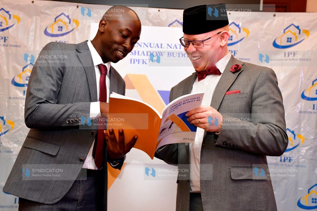 IPF Chief Executive Officer James Muraguri reads through a report with Office of the Prime Cabinet Secretary CAS Isaac Mwaura