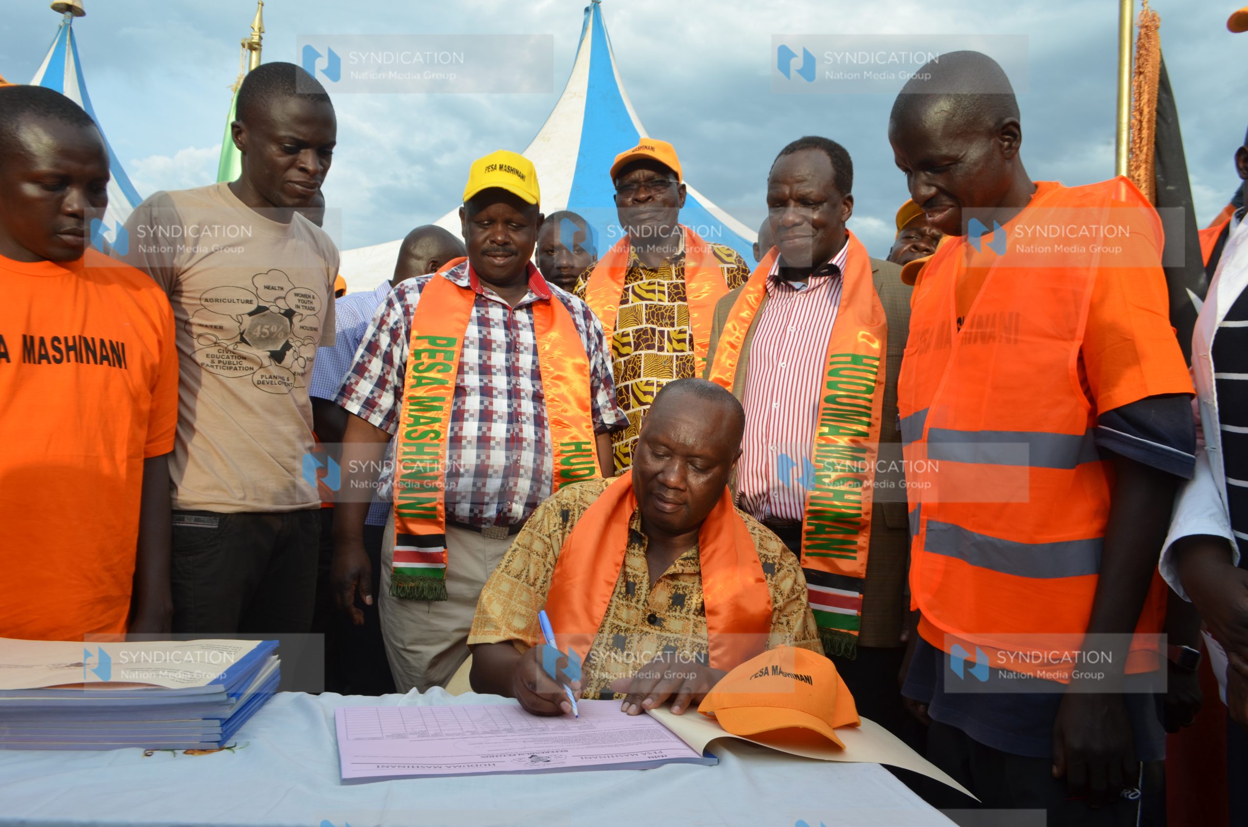 Busia Governor Sospeter Ojaamong signs the “Pesa Mashinani” book in Malaba Town