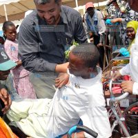 Abdulswamad Nassir, helps one of the persons with disabilities to sit on a chair