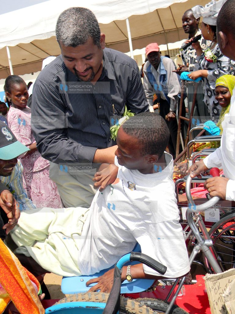 Abdulswamad Nassir, helps one of the persons with disabilities to sit on a chair