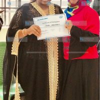 Nominated Senator Millicent Omanga awards a certificate to one of the 120 women trained in computer skills