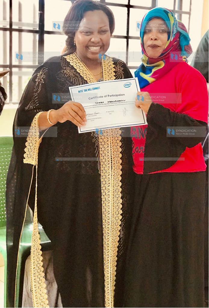 Nominated Senator Millicent Omanga awards a certificate to one of the 120 women trained in computer skills