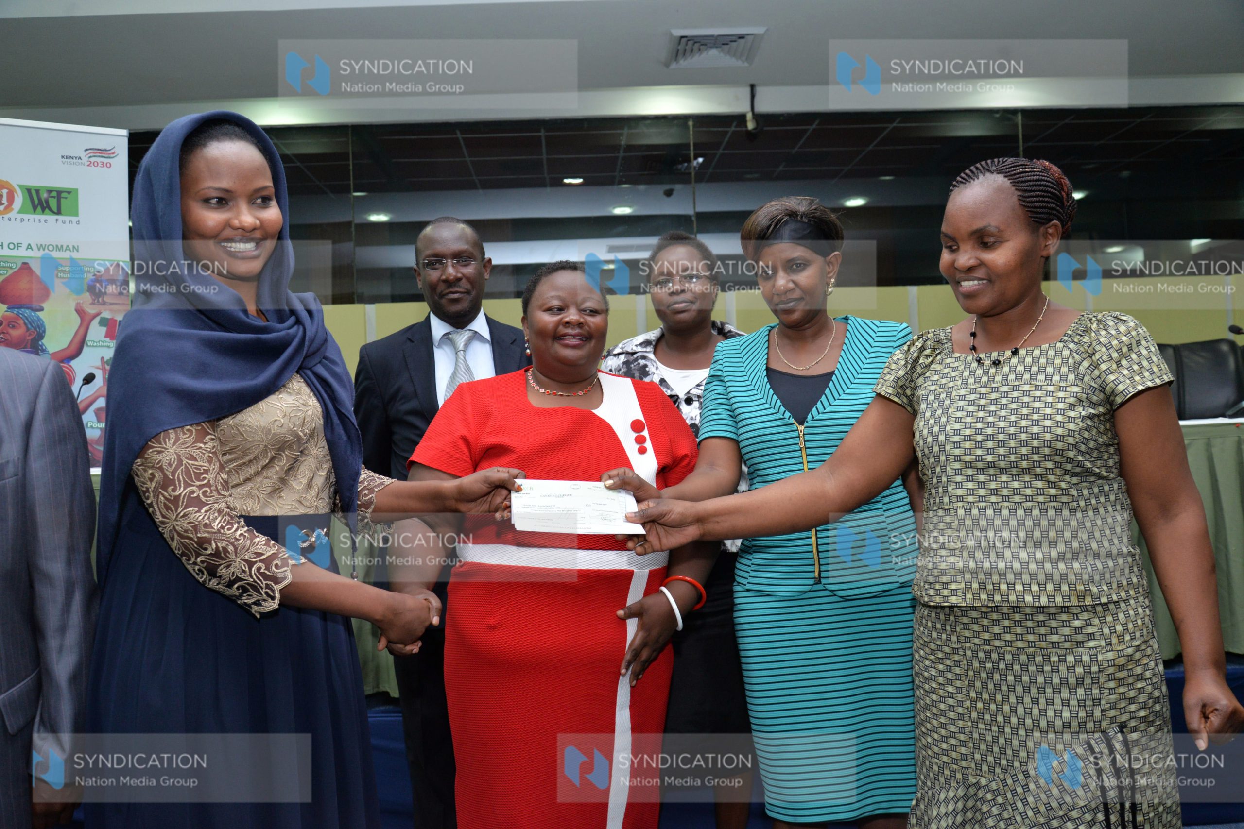 Women Enterprise Fund Advisory Board chairperson, Mumina Bonaya (left) present a cheque of Kshs.500,000/=