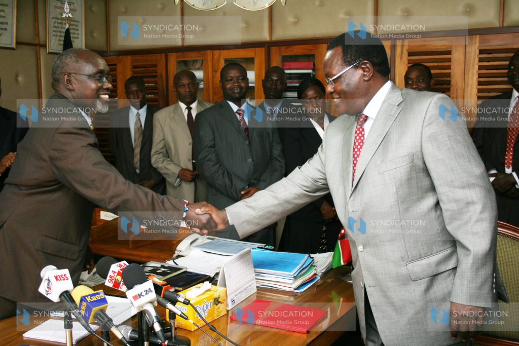 Roads Minister Mr. Franklin Bett, shakes hands with Minister Chris Obure